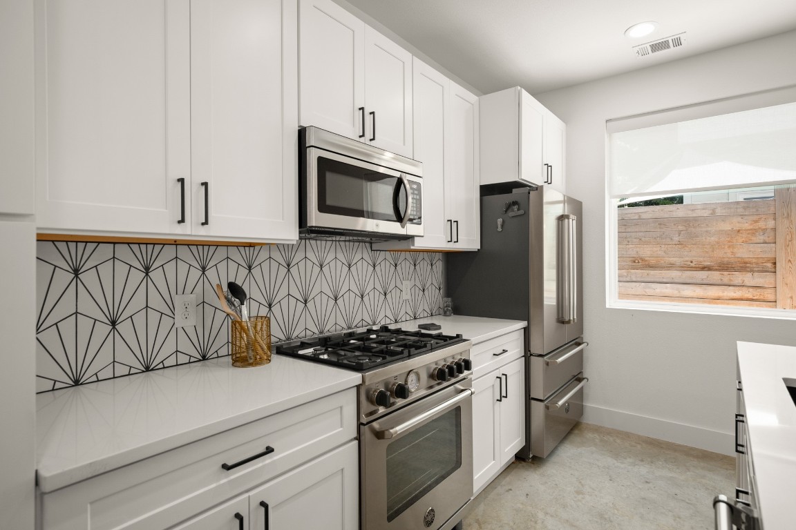 a kitchen with stainless steel appliances a stove a microwave and white cabinets