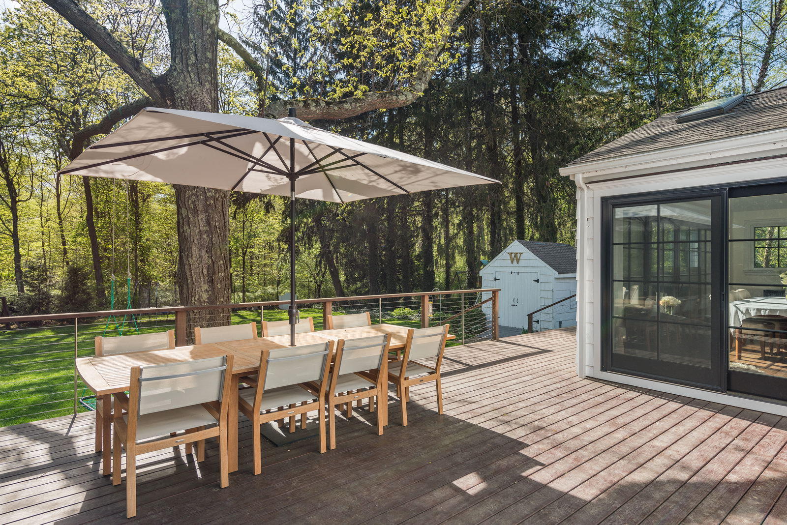 19 Birch Road Darien, CT 06820 - Photo 4 of 21 a view of a patio with a dining table and chairs under an umbrella with a barbeque grill and a small yard