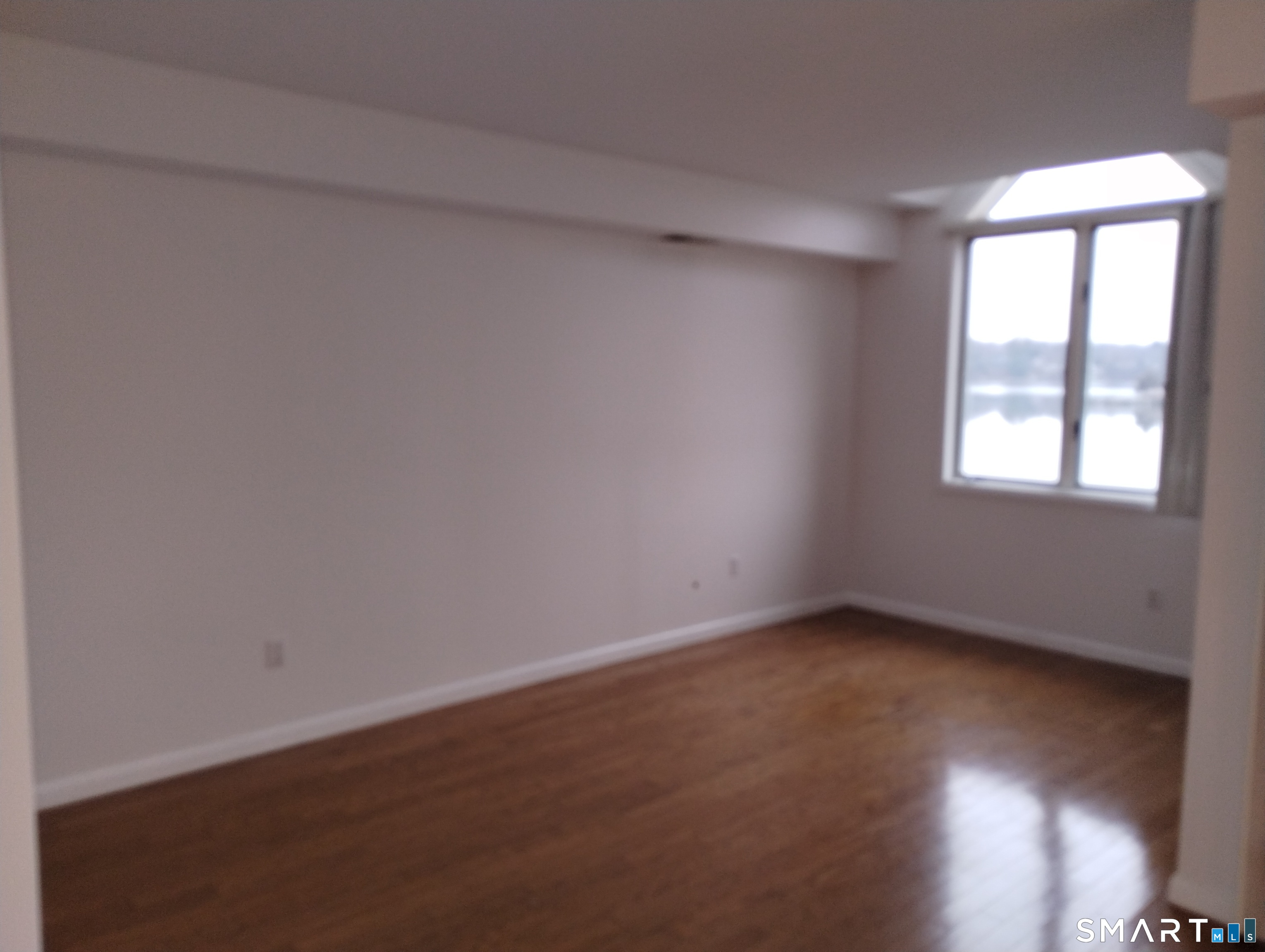 523 Popes Island Road, Unit 523 Milford, CT 06461 - Photo 18 of 33 an empty room with wooden floor and windows
