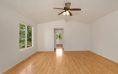 a view of empty room with wooden floor and fan