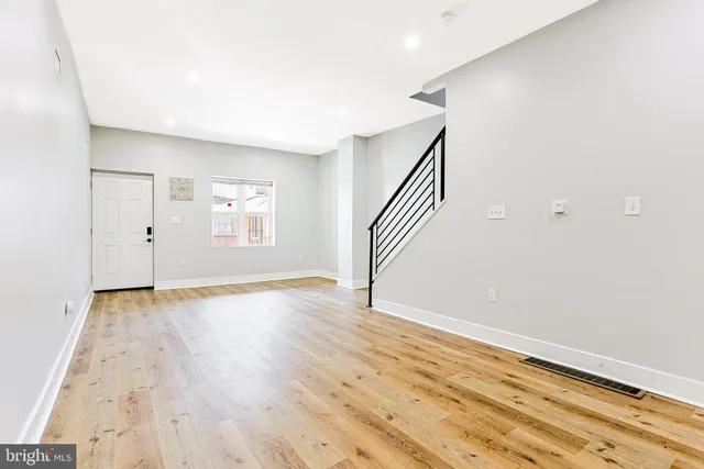 a view of an empty room with wooden floor and stairs