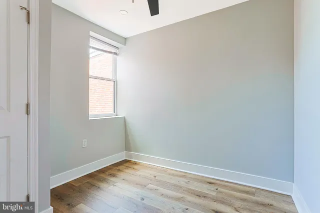 a view of an empty room with wooden floor and a window