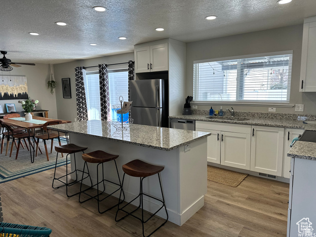 702 North 100 West Logan, UT 84321 - Photo 46 of 58 Kitchen featuring light wood finished floors, a sink, a center island, and appliances with stainless steel finishes