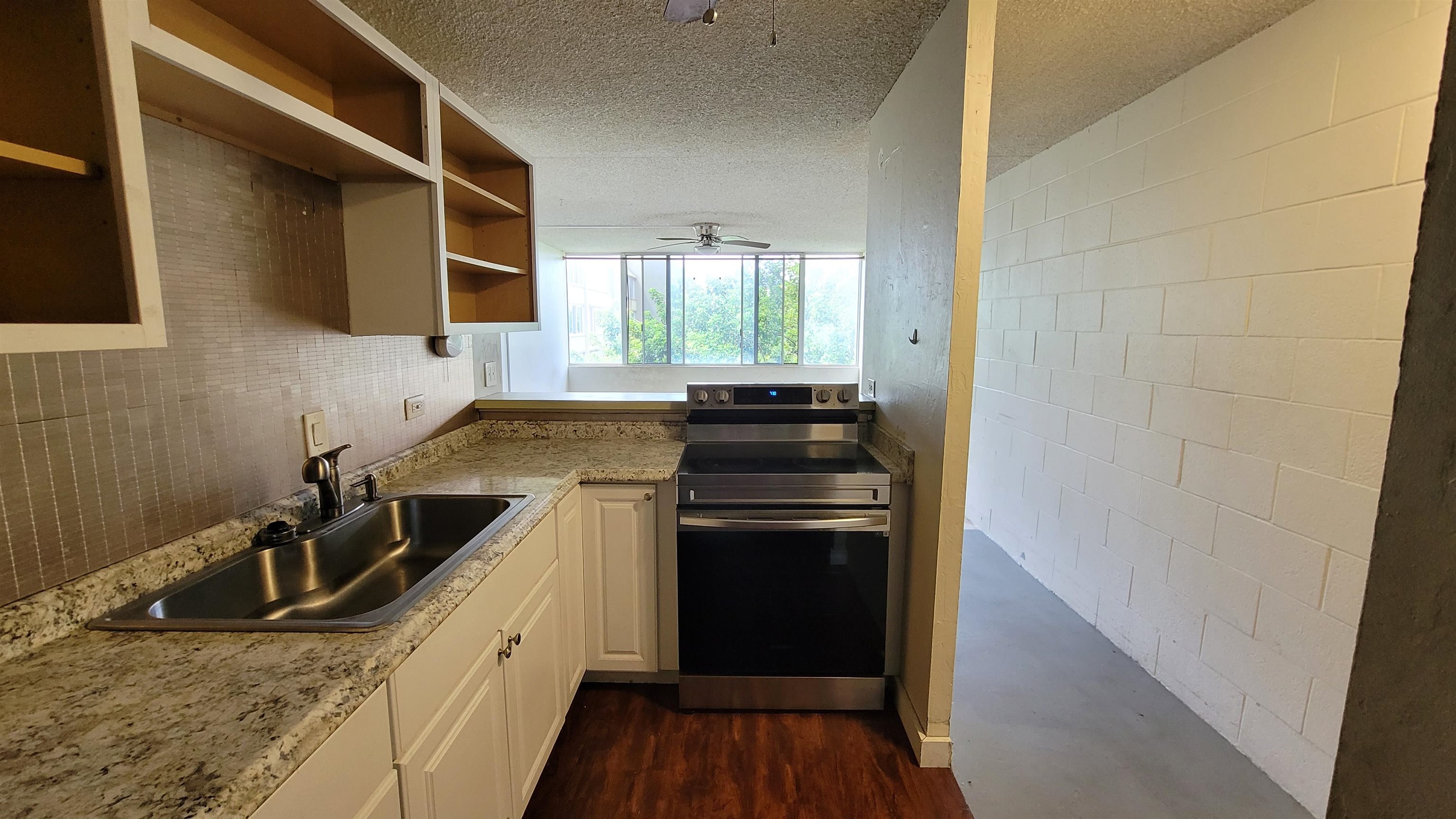 a kitchen with granite countertop a sink stove and refrigerator