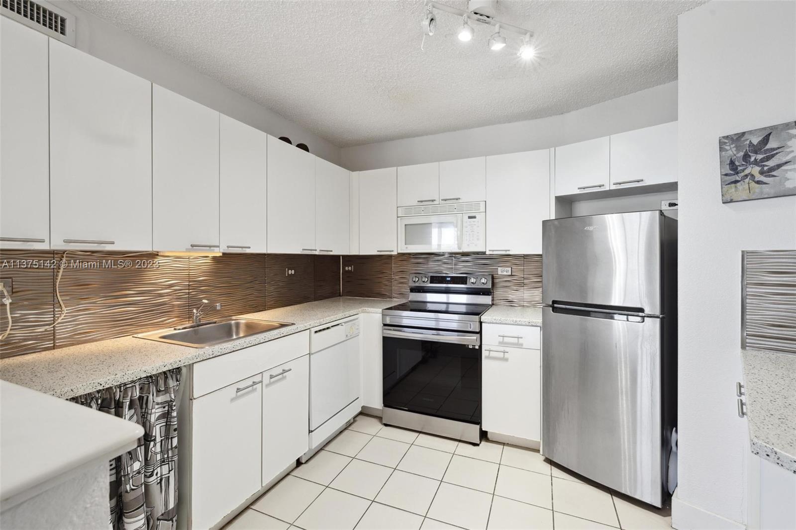 1500 Bay Road, Unit 1556S Miami Beach, FL 33139 - Photo 11 of 13 a kitchen with white cabinets and stainless steel appliances