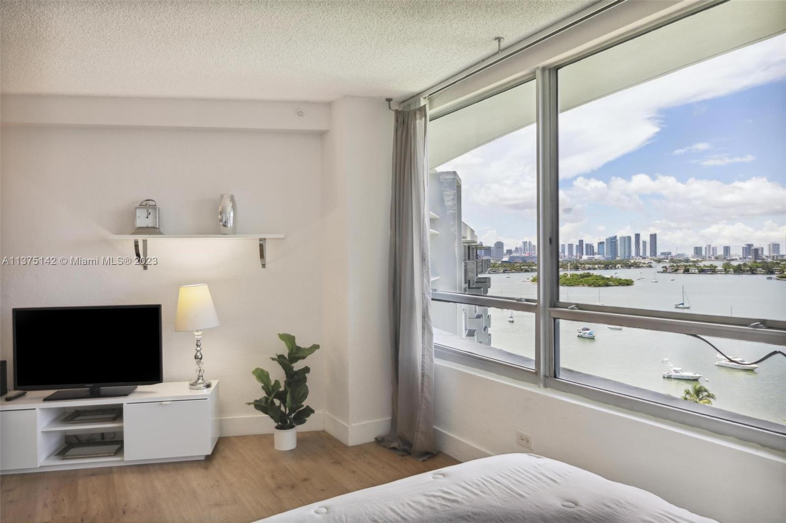 1500 Bay Road, Unit 1556S Miami Beach, FL 33139 - Photo 3 of 13 a living room with a large window and a flat screen tv
