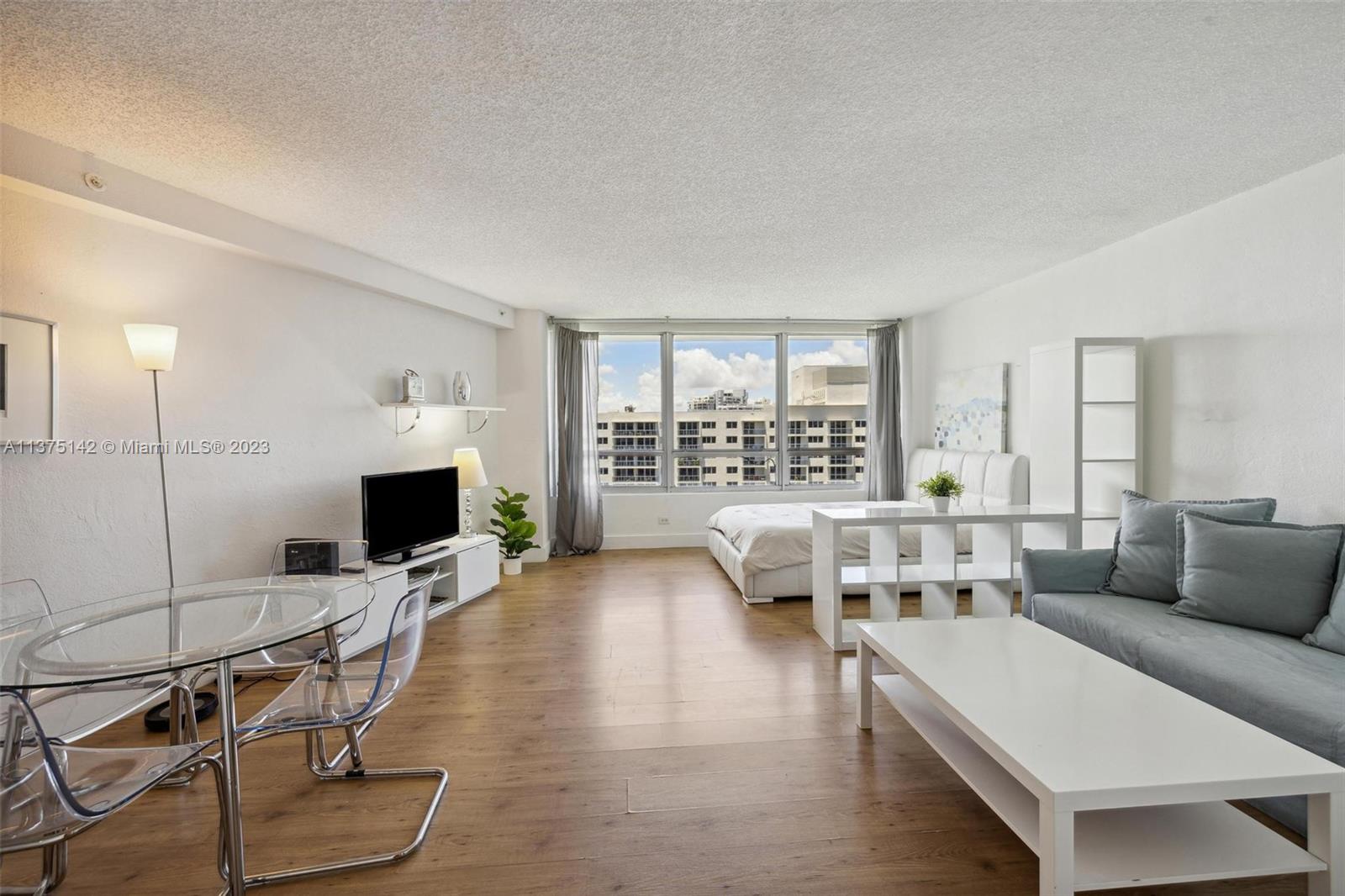 1500 Bay Road, Unit 1556S Miami Beach, FL 33139 - Photo 4 of 13 a living room with furniture and a flat screen tv with kitchen view