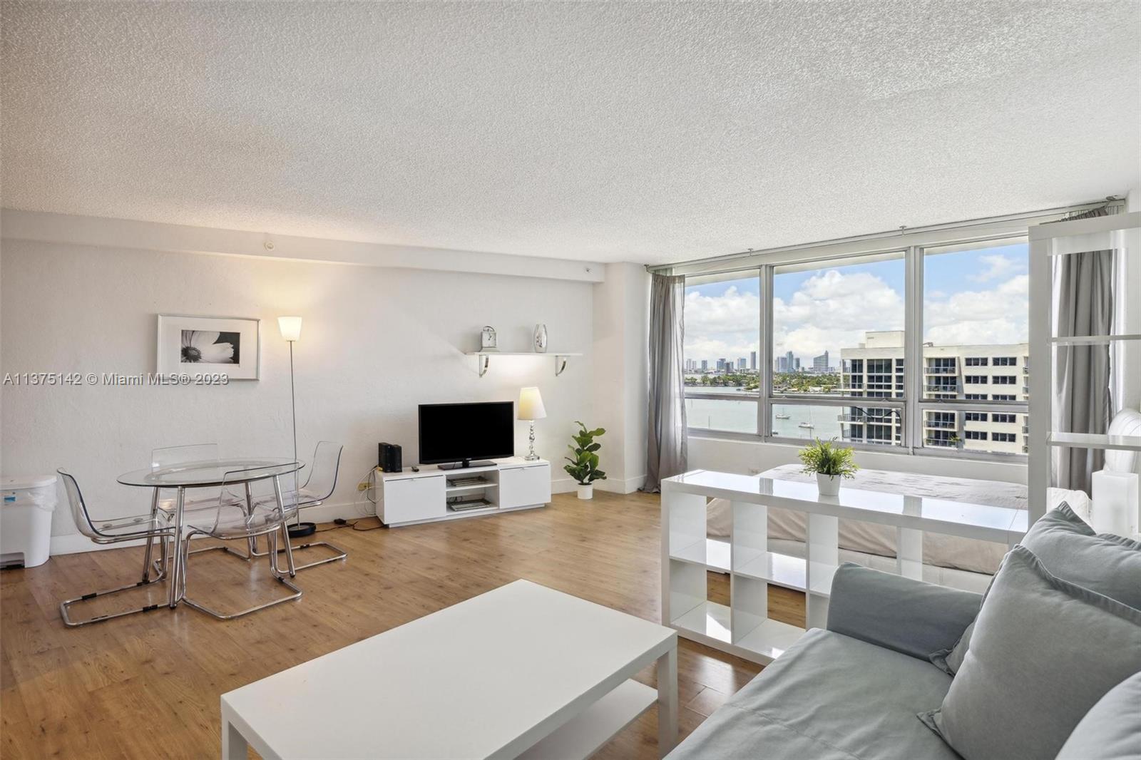 1500 Bay Road, Unit 1556S Miami Beach, FL 33139 - Photo 5 of 13 a living room with furniture a large window and a flat screen tv