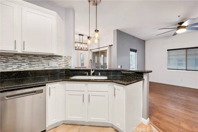 a kitchen with granite countertop a sink cabinets and stainless steel appliances