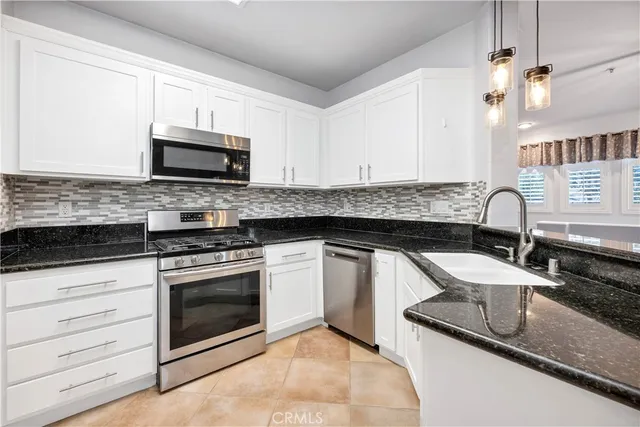 a kitchen with granite countertop a sink stove and microwave