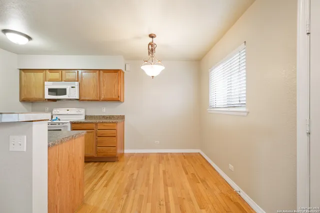 a kitchen with granite countertop wooden floors a sink and a microwave