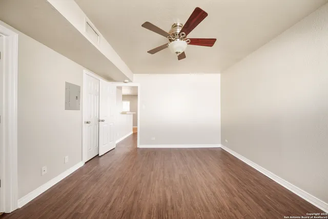 a view of a big room with wooden floor and windows