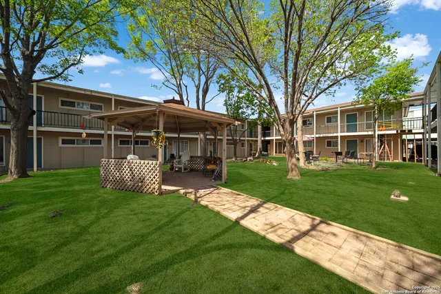 a view of a house with a yard deck and a large tree