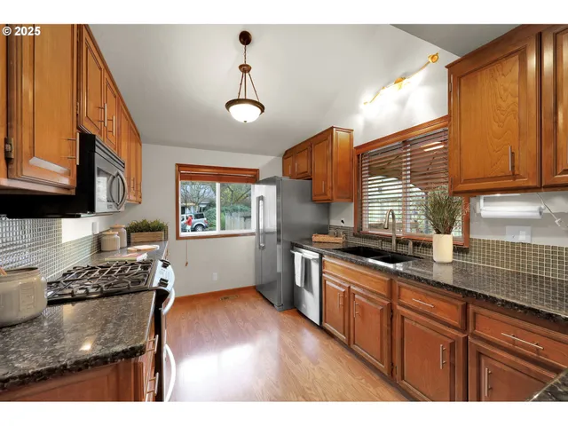 a kitchen with granite countertop wooden cabinets stainless steel appliances and a window