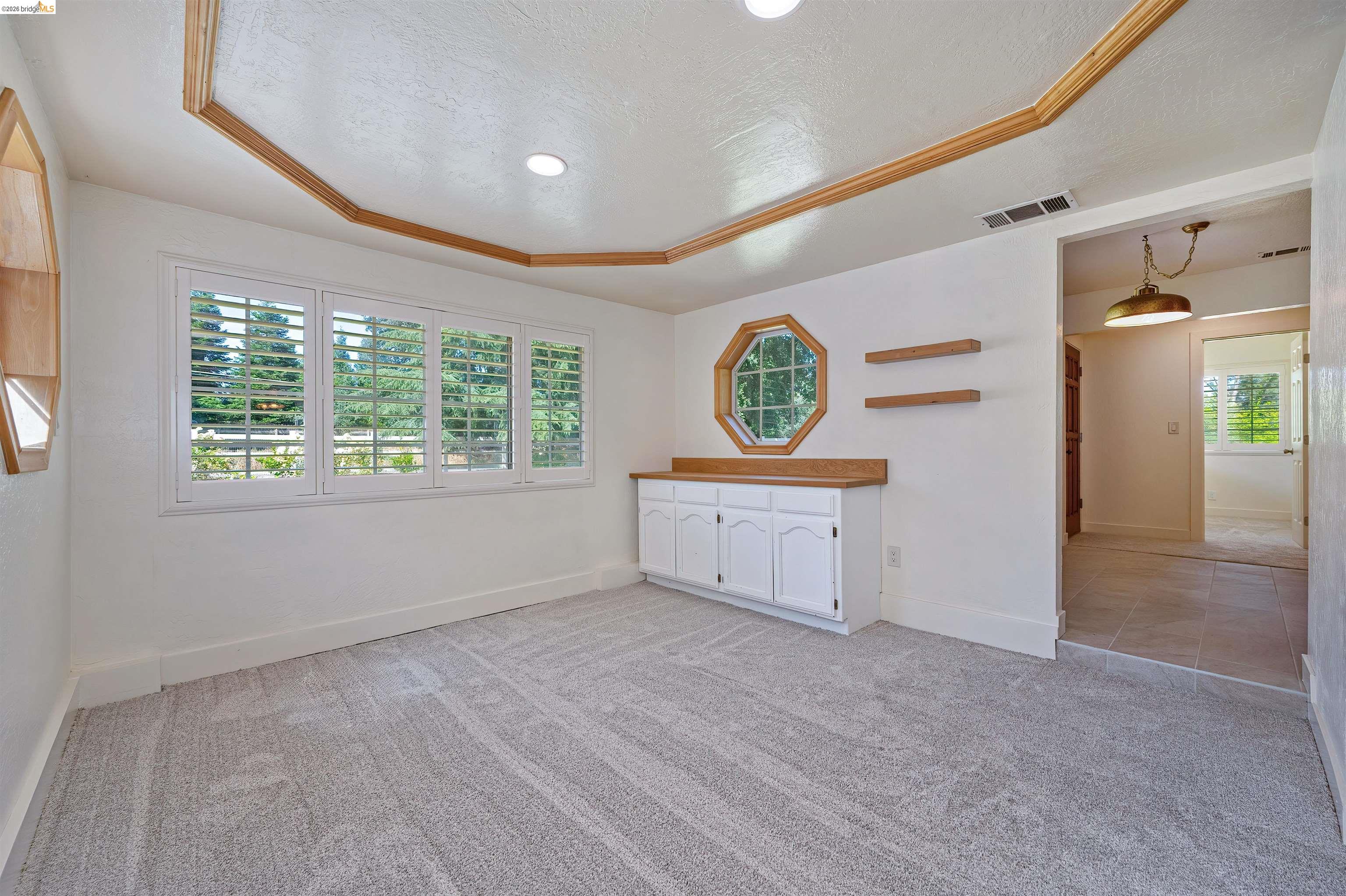 10474 Sheldon Road Elk Grove, CA 95624 - Photo 15 of 83 Carpeted interior space featuring a multi-pane window with plantation shutters, a built-in cabinet with a wood-finish countertop, and decorative wood trim on the ceiling