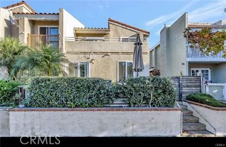 a view of a white house with large windows and a yard with plants