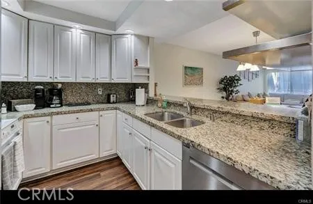 a kitchen with granite countertop a sink a stove and cabinets