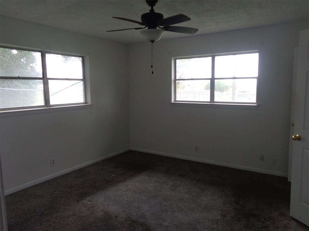612 South Files Street Itasca, TX 76055 - Photo 19 of 30 Unfurnished room with dark carpet, healthy amount of natural light, and a ceiling fan