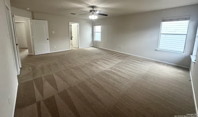 an empty room with windows and fan