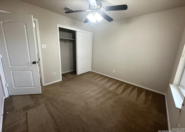 an empty room with closet and a chandelier fan