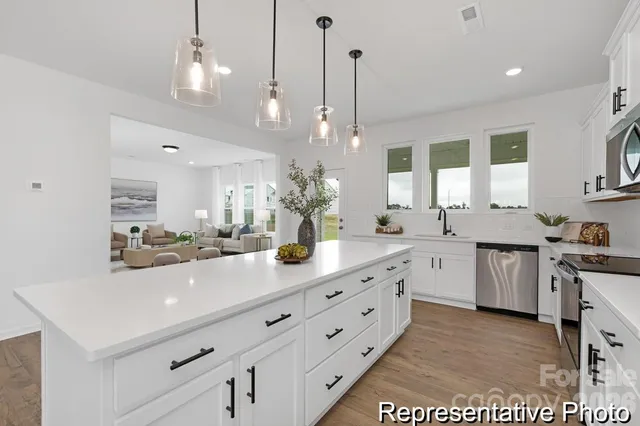 a kitchen with sink stove and white cabinets with wooden floor