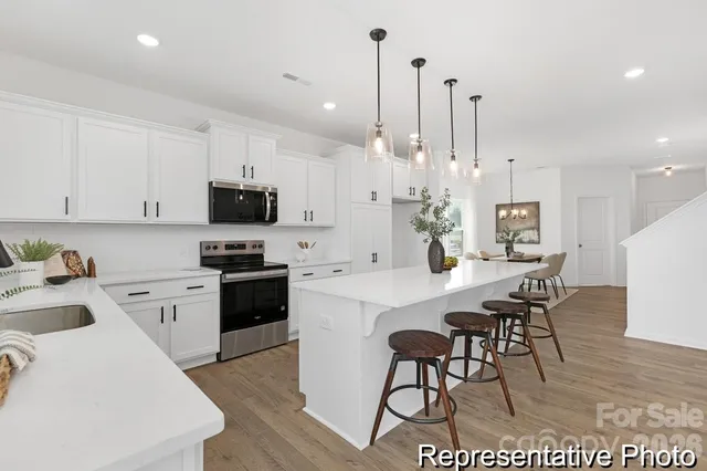 a kitchen with kitchen island a white counter top space a sink stainless steel appliances and cabinets