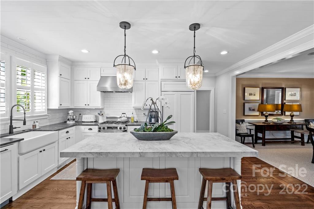 2156 Colony Road Charlotte, NC 28209 - Photo 16 of 46 a kitchen with a dining table chairs stove and white cabinets
