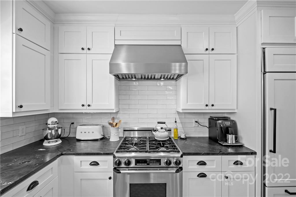 2156 Colony Road Charlotte, NC 28209 - Photo 20 of 46 a kitchen with granite countertop a stove a sink and white cabinets