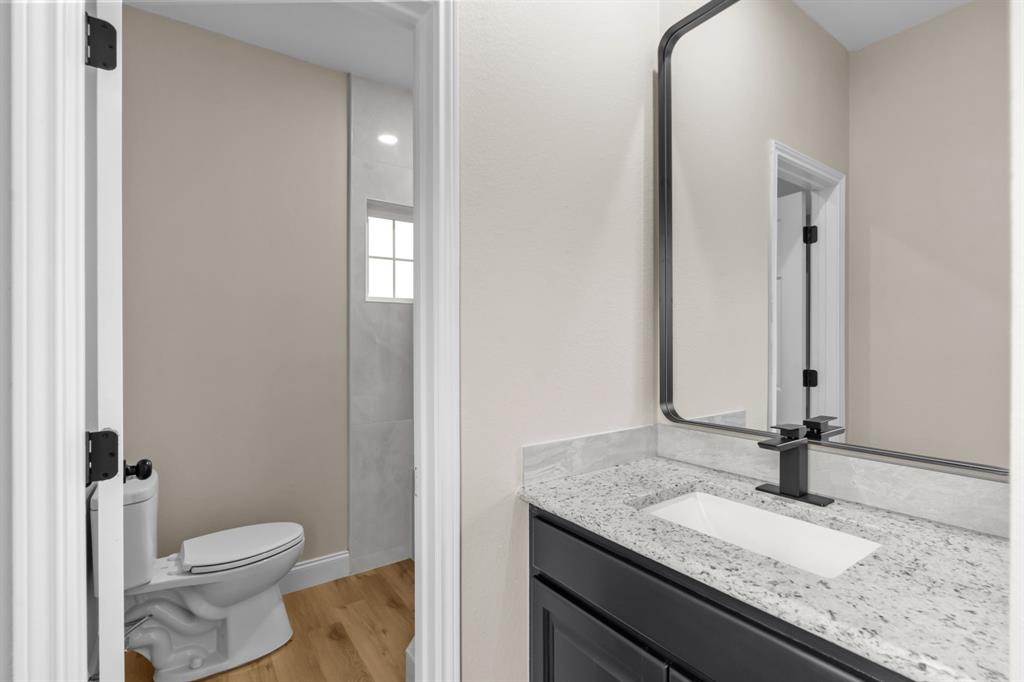 4510 Dexham Road Rowlett, TX 75088 - Photo 19 of 33 a bathroom with a granite countertop sink a toilet and a mirror