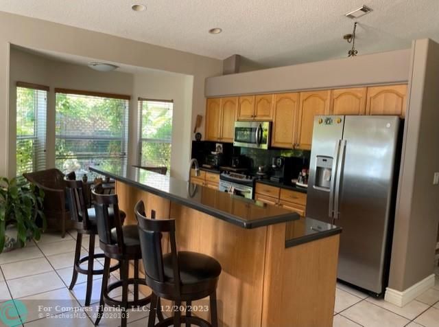 Keystone Lake Pembroke Pines, FL 33029 - Photo 10 of 23 a kitchen with stainless steel appliances granite countertop a stove a refrigerator a sink a dining table and chairs with the ocean view