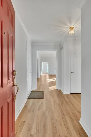 a view of a hallway with wooden floor and a bathroom