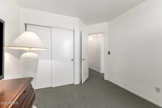 a view of a white house with a yard and table and chairs under an umbrella