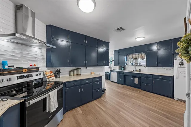 a large kitchen with stainless steel appliances wooden cabinets and a stove top oven