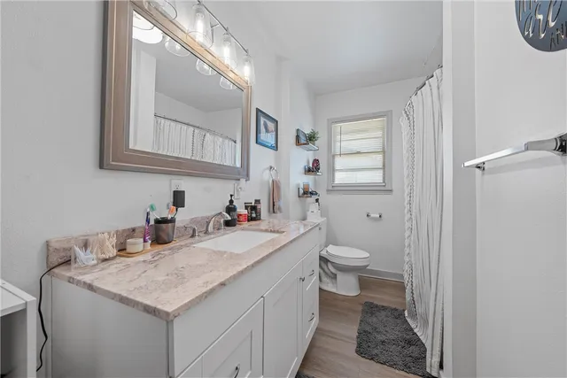 a bathroom with a granite countertop sink a toilet and a mirror