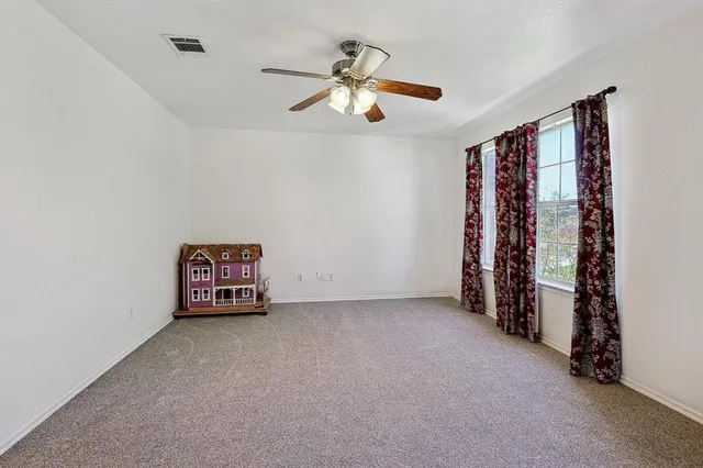 a view of an empty room with a ceiling fan and window