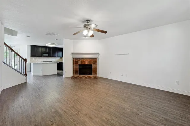 a view of an empty room with a kitchen and a fireplace
