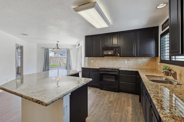 a kitchen with granite countertop a sink a counter top space and cabinets
