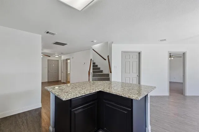 a kitchen with granite countertop kitchen island wooden cabinets and refrigerator