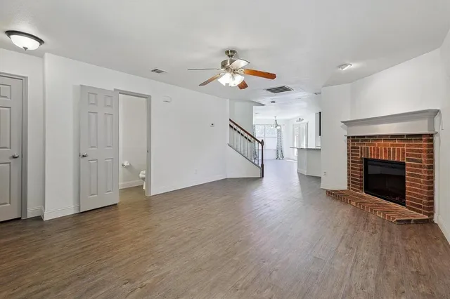 an empty room with wooden floor fireplace and windows