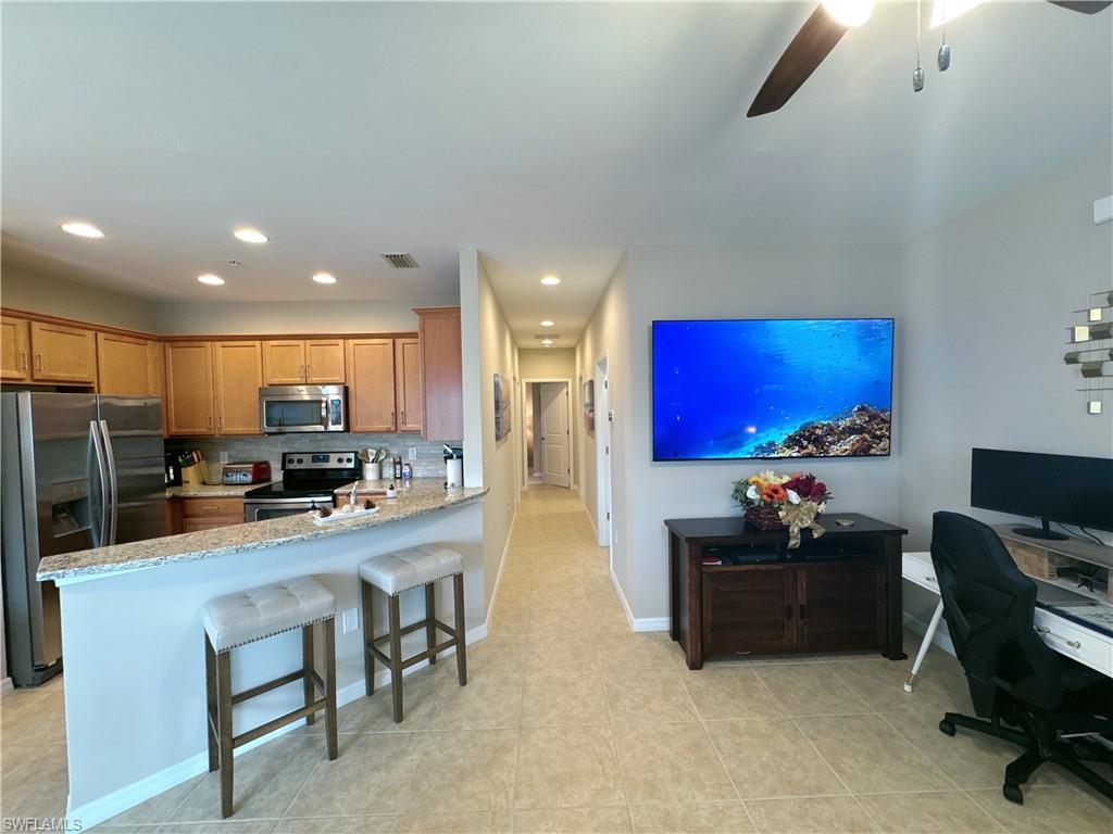 1431 Santiago Circle, Unit 1901 Naples, FL 34113 - Photo 7 of 29 a kitchen with stainless steel appliances kitchen island granite countertop a stove top oven a sink a dining table and chairs