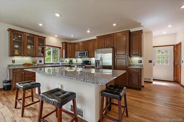 a kitchen with stainless steel appliances granite countertop wooden cabinets a refrigerator a stove a sink and a oven