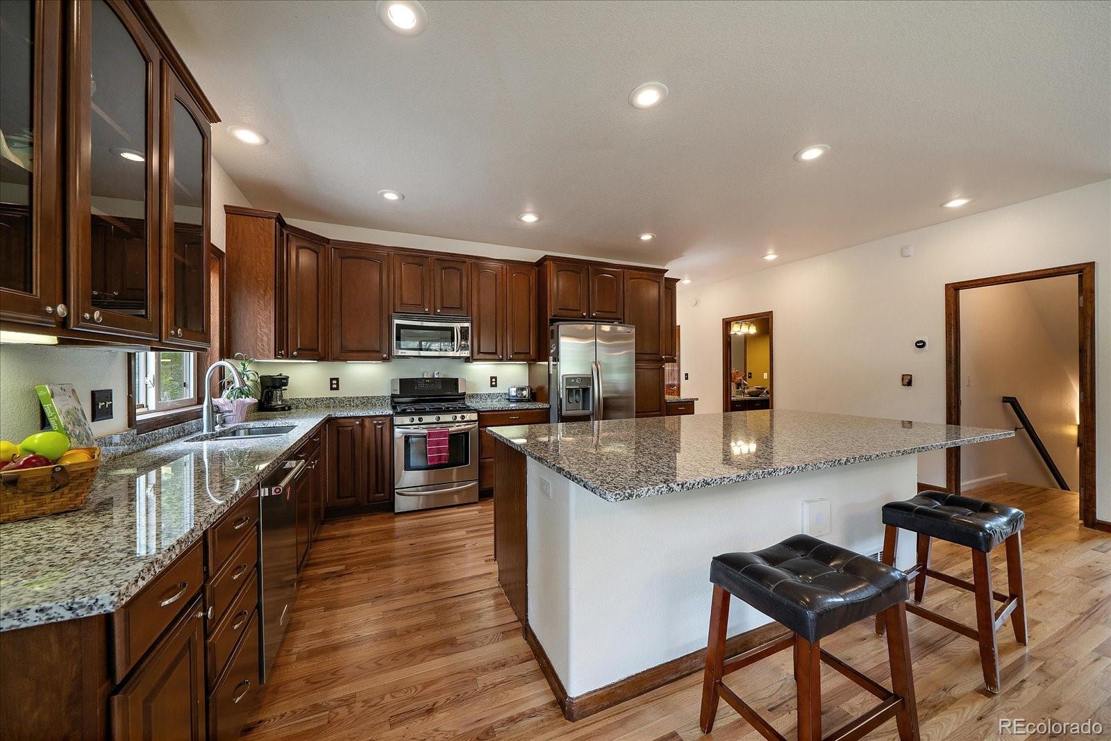 27756 Troublesome Gulch Road Evergreen, CO 80439 - Photo 17 of 47 a kitchen with stainless steel appliances granite countertop wooden cabinets a refrigerator a stove a sink and a oven