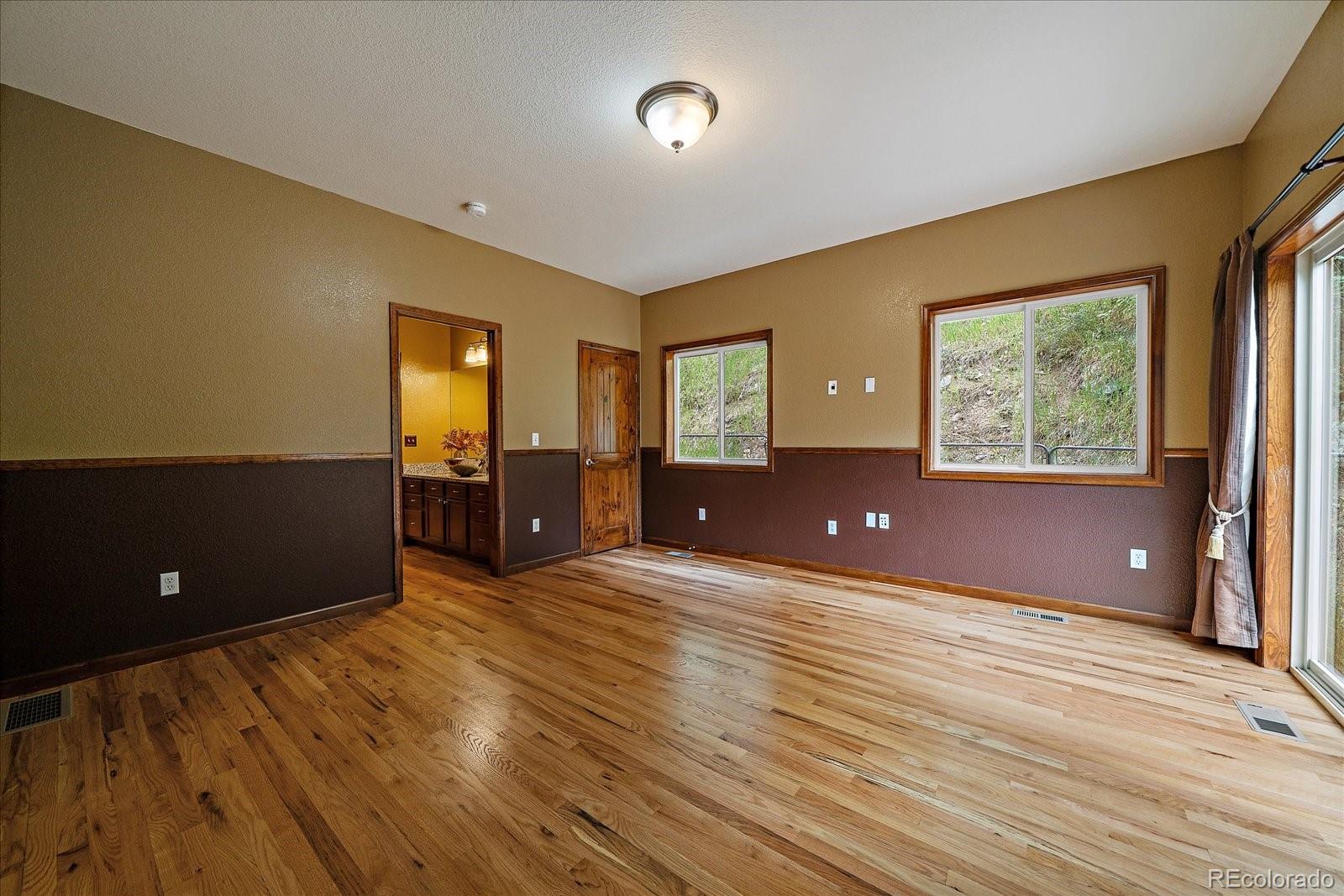 27756 Troublesome Gulch Road Evergreen, CO 80439 - Photo 20 of 47 a view of a room with wooden floor and windows