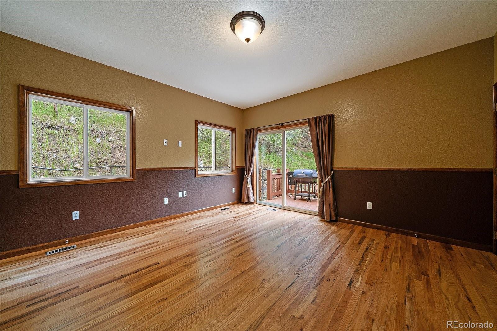 27756 Troublesome Gulch Road Evergreen, CO 80439 - Photo 21 of 47 a view of an empty room with wooden floor and a window