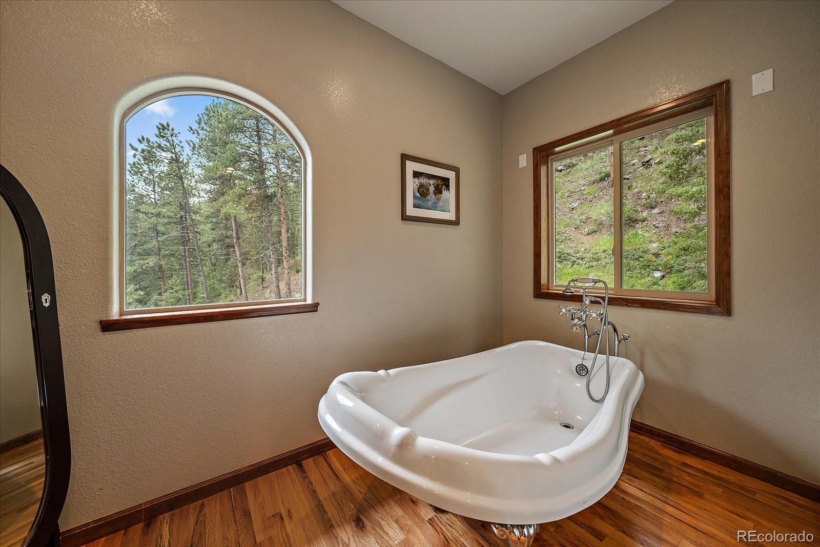 27756 Troublesome Gulch Road Evergreen, CO 80439 - Photo 29 of 47 a white bath tub sitting in a bathroom next to a window