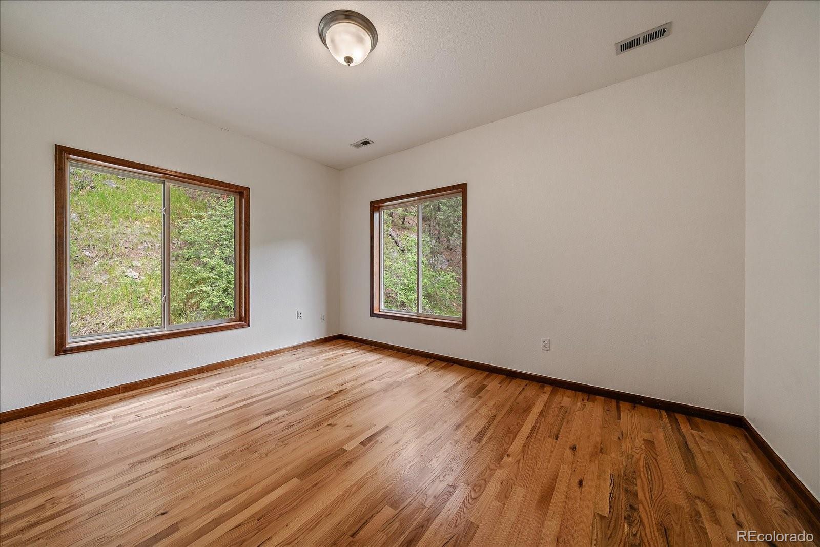 27756 Troublesome Gulch Road Evergreen, CO 80439 - Photo 30 of 47 an empty room with wooden floor and windows