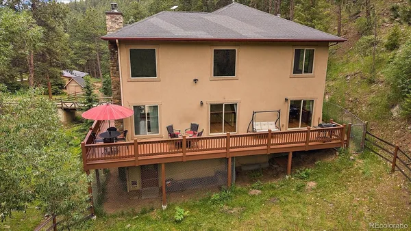 a house that has glass top table and chairs under an umbrella