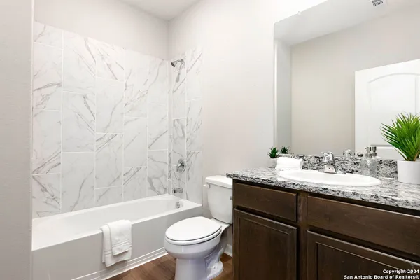 a bathroom with a granite countertop sink toilet mirror and bathtub