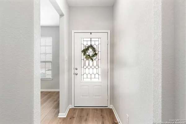 an entryway to room with wooden floor mirror and windows