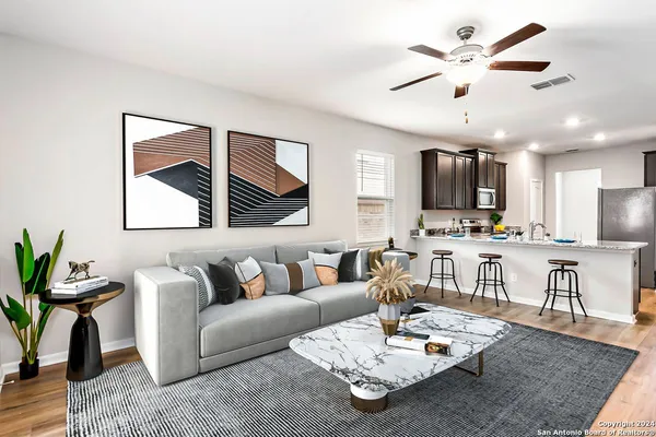 a living room with furniture kitchen view and a wooden floor